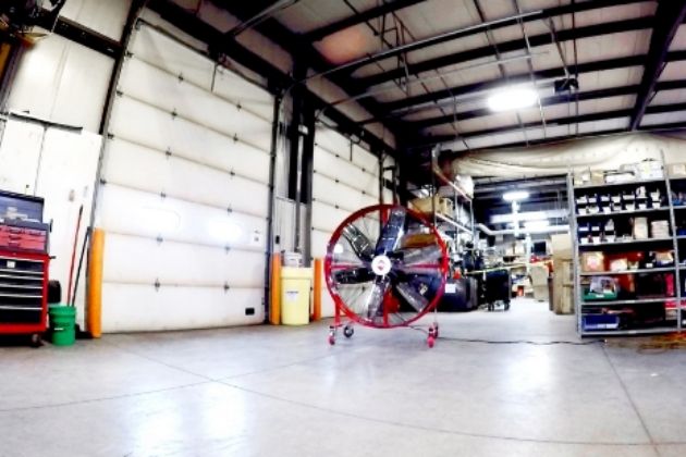 Portable industrial fan on wheels in a garage.
